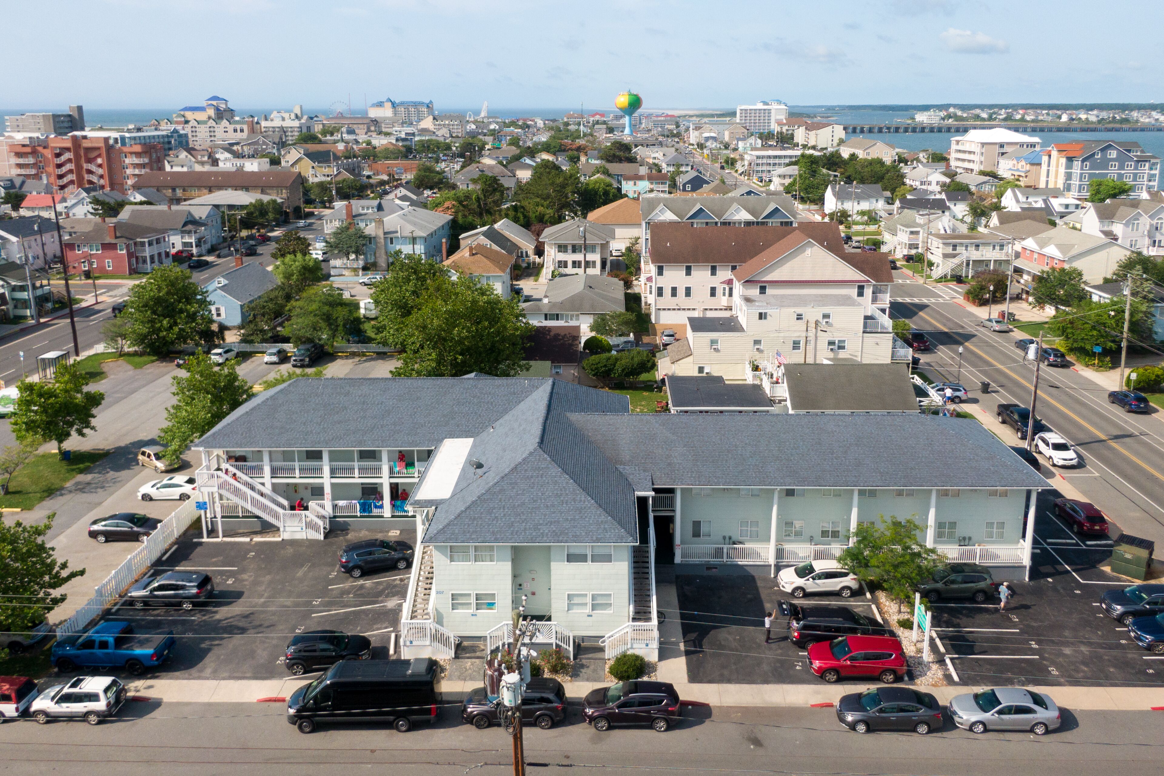 A multi-story building with a parking lot in front, surrounded by other residential buildings.