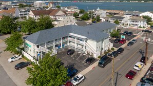 A multi-story hotel with a parking lot, located near a waterfront.