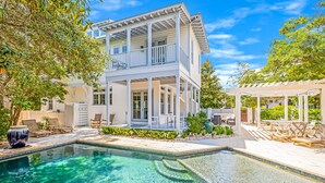 Une maison à deux étages avec une piscine, un espace salon extérieur et une pergola.