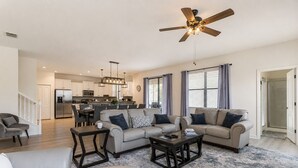 Ein geräumiges Wohnzimmer mit einer großen Eckcouch, einem Couchtisch und einem Deckenventilator.