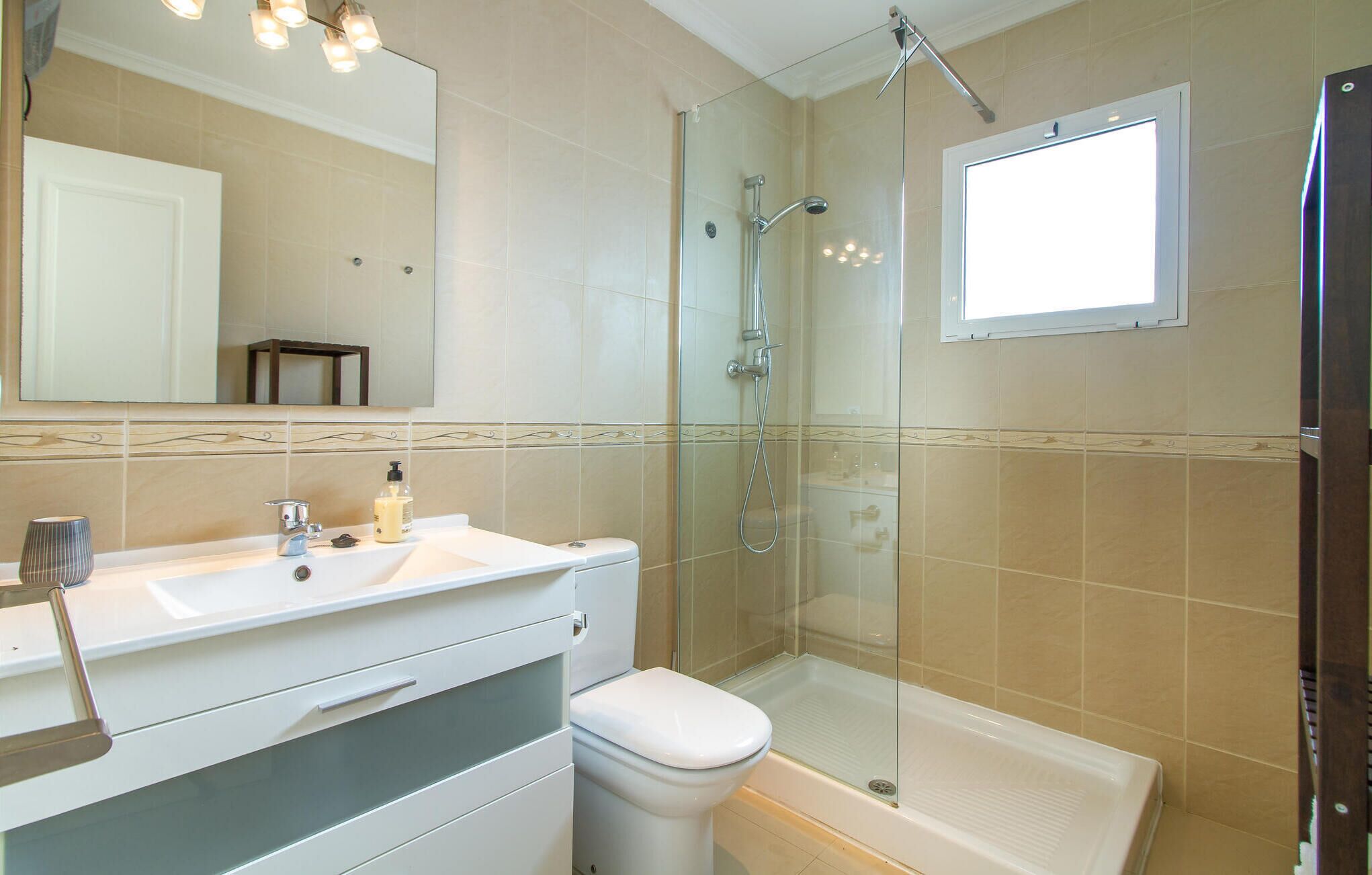 Une salle de bain moderne avec une douche à parois de verre, un lavabo blanc et des toilettes.