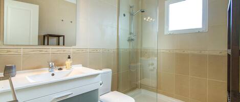Une salle de bain moderne avec une douche à parois de verre, un lavabo blanc et des toilettes.