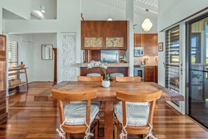 A modern kitchen with wooden cabinets, a large island, and a dining area with a wooden table and chairs.