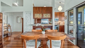 Een moderne keuken met houten kastjes, een groot eiland en een eethoek met een houten tafel en stoelen.
