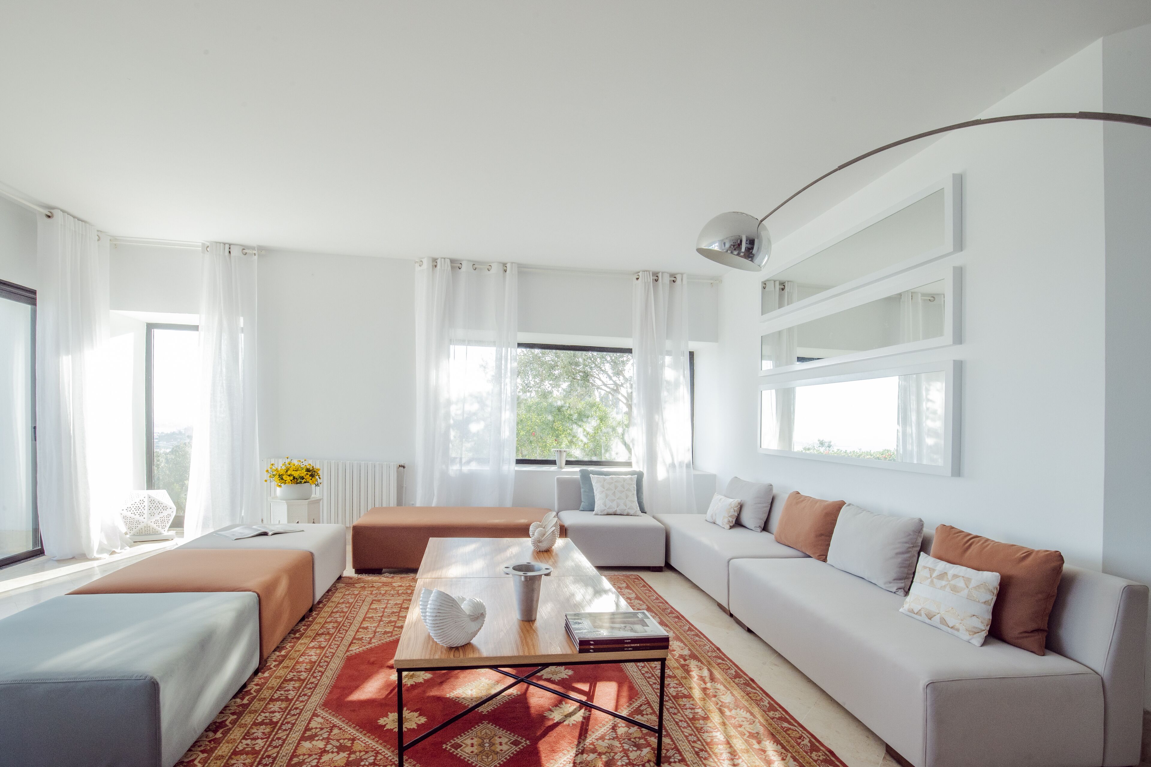 Una sala de estar moderna con un conjunto de sofás, una mesa de centro y un ventanal con cortinas.