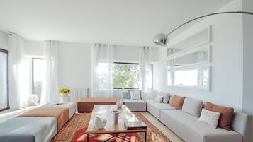Una sala de estar moderna con un conjunto de sofás, una mesa de centro y un ventanal con cortinas.