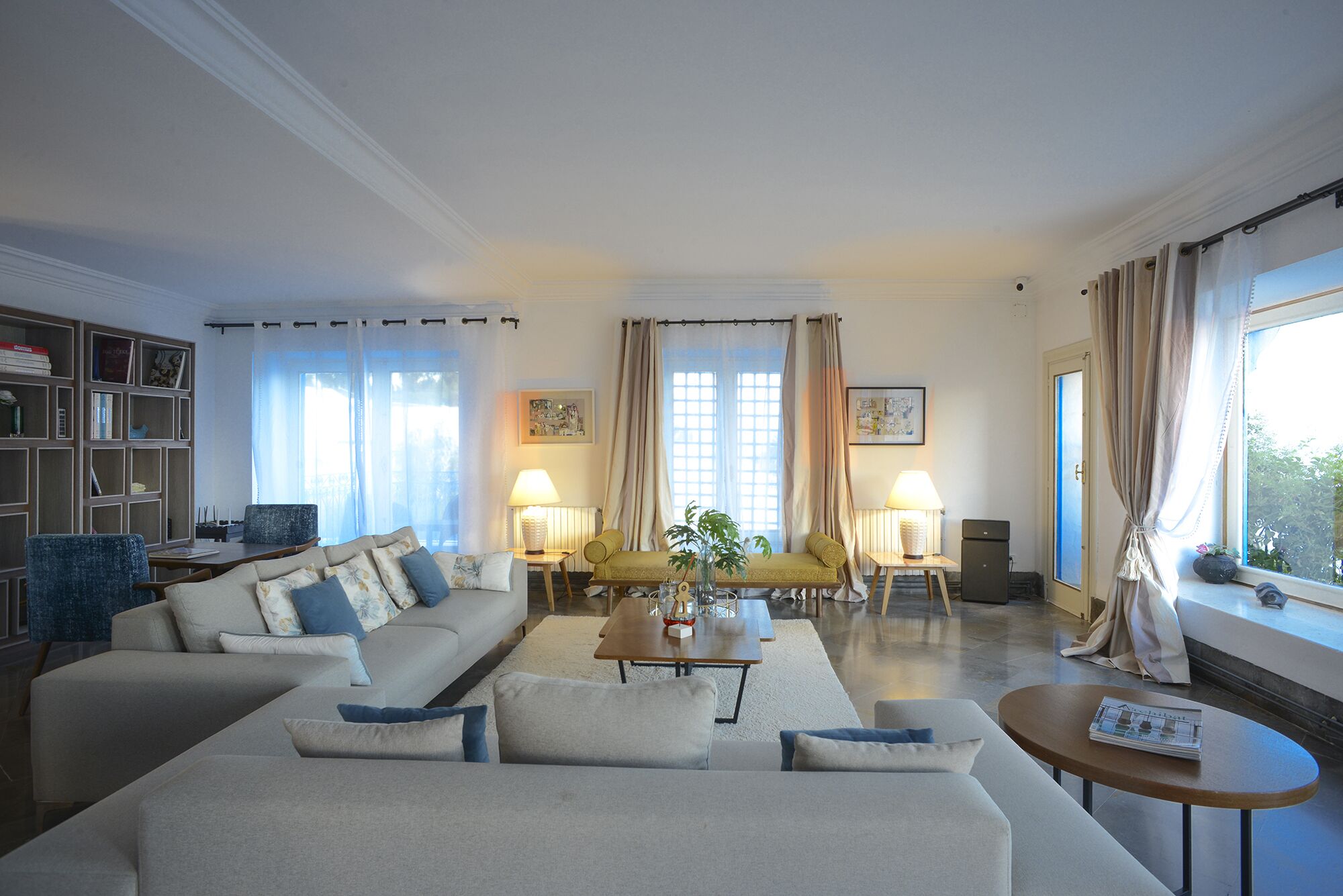 Una sala de estar con un sofá, sillones, una mesa de centro y una estantería.