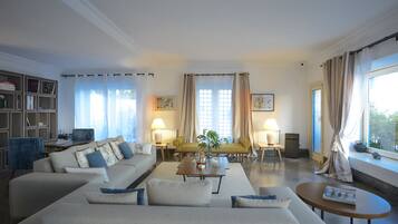 Una sala de estar con un sofá, sillones, una mesa de centro y una estantería.