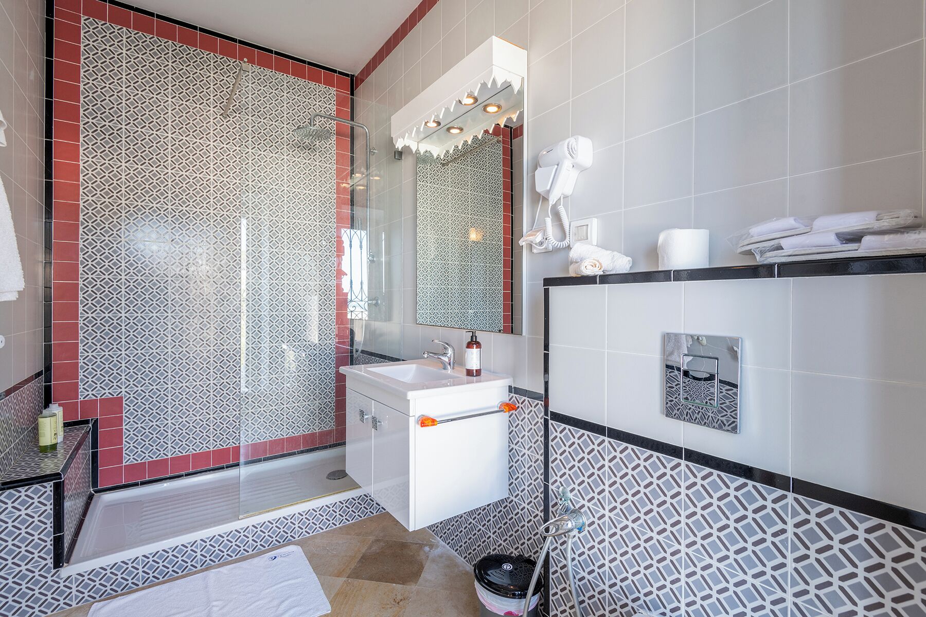 Un baño moderno con cabina de ducha de vidrio, un lavamanos blanco y un espejo encima.