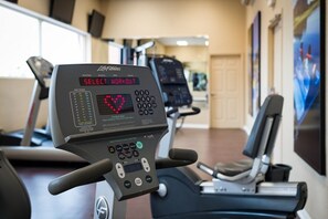 A treadmill with a digital display and control panel in a gym setting.