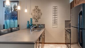 Una cocina moderna con una isla grande, electrodomésticos de acero inoxidable y decoración mural.