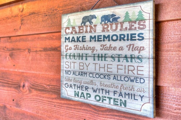 A wooden cabin with a sign listing cabin rules such as 'Go Fishing, Take a Nap, Count the Stars, Sit by the Fire, No Alarm Clocks Allowed, Take Long Walks, Breathe Fresh Air, Gather with Family, Nap Often'. - A View From Above - Dog Friendly w/ Screened in Porch and Hot Tub, Near Helen GA (Sautee Nacoochee)