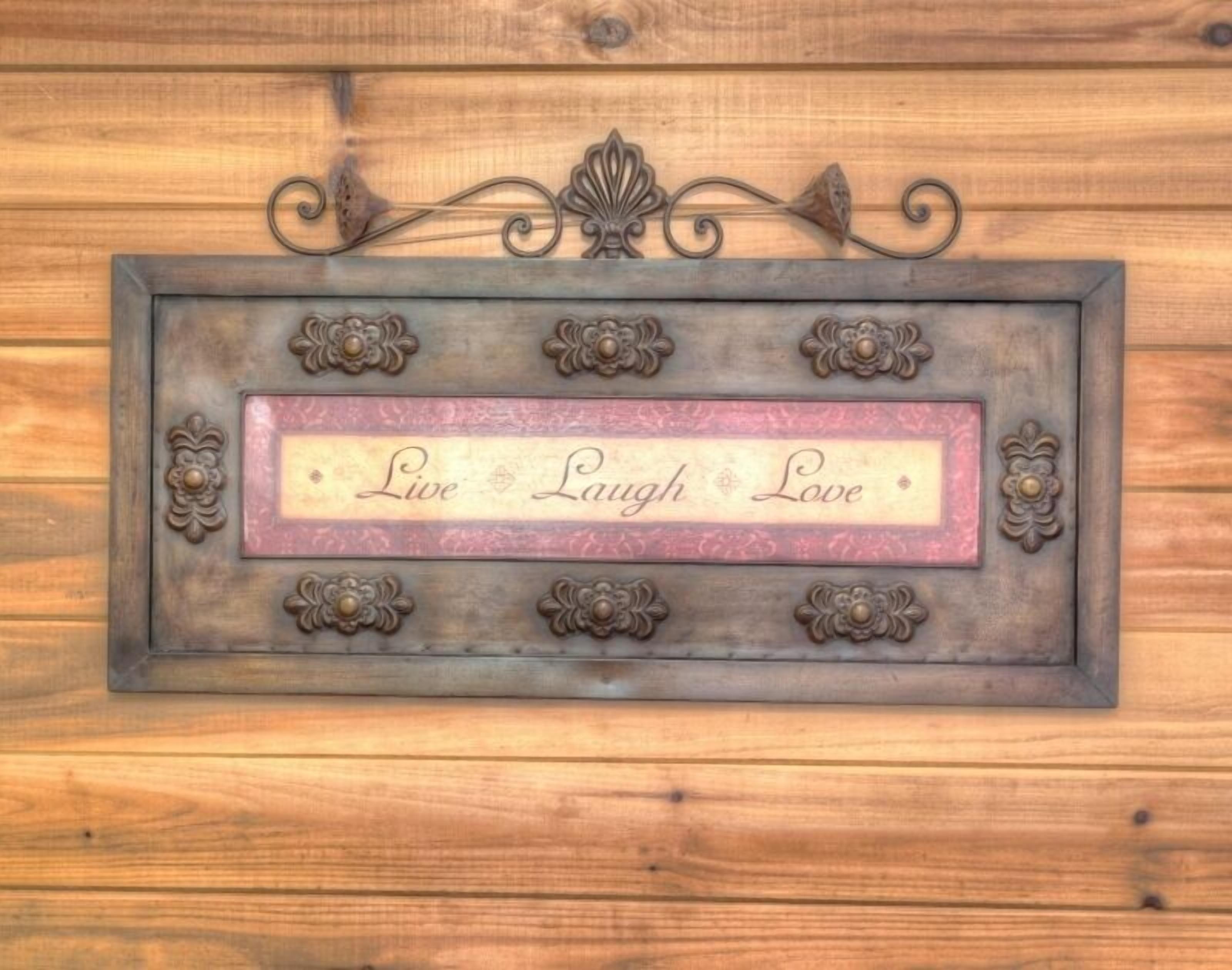 Een decoratief bord met de tekst 'Live Laugh Love' op een houten achtergrond.