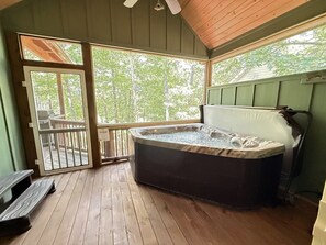 Un bain Ă remous dans une piĂšce en bois avec vue sur les arbres.