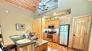 A kitchen with wooden cabinets, a stainless steel refrigerator, and a microwave.