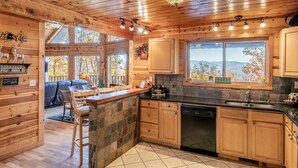 Une cuisine de style rustique, avec des murs en bois, un pare-feu en pierre et une grande fenêtre donnant sur les montagnes.