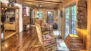 A rustic wooden interior with a fireplace, rocking chairs, and a large wooden head sculpture. - Delaine`s Retreat - 4 BR Cabin, Dog Friendly, Walkable to Downtown Helen, GA (Helen)