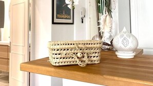A wooden table with a woven basket, a vase with white orchids, and a white decorative item. - (008) Cosy & Chic Old Town (Antibes)