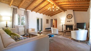 A spacious living room with a high wooden ceiling, a fireplace, and a television. - Quinta Molinum Ad Mare | 8 Bedrooms | Sea Views | Boliqueime (Boliqueime)