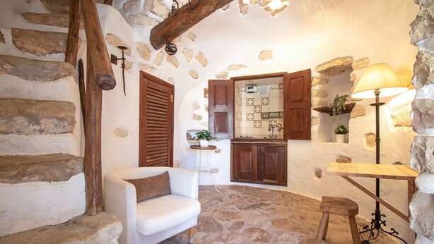 A stone-walled room with a white sofa, wooden table, and a small stool. - Quinta Molinum Ad Mare | 8 Bedrooms | Sea Views | Boliqueime (Boliqueime)