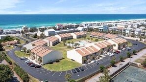 A coastal residential area with multiple buildings, a parking lot, and a view of the ocean. - 10 H Two Bedroom Condo (Miramar Beach)