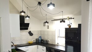 Una cocina moderna con muebles de color negro y blanco, una isla central, iluminación colgante y horno empotrado.