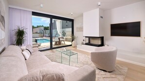 A modern living room with a beige sofa, a glass coffee table, and a fireplace.