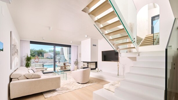 A modern living room with a glass staircase, a pool view, and a minimalist design.
