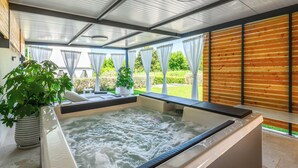 A spa area with a hot tub, potted plants, and a view of the garden.