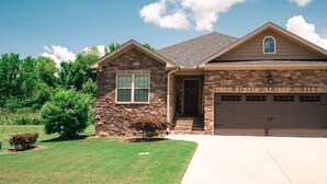 A two-story house with a stone facade, a garage, and a well-maintained lawn.