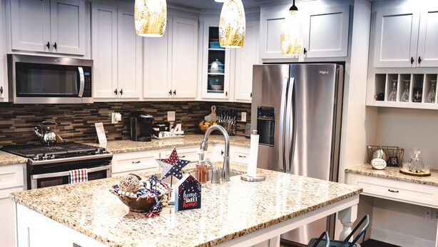 A modern kitchen with granite countertops, stainless steel appliances, and white cabinetry.