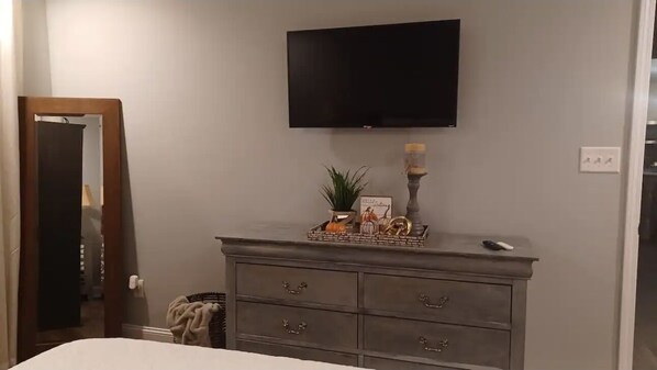 A bedroom with a bed, a dresser, a flat-screen TV mounted on the wall, and a small potted plant on the dresser. - Cozy Newly built home located in RAINBOW CITY Al convenient to highway 759 & 59 (Rainbow City)
