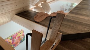 Eine Holzbank mit Kissen, einer gewebten Matte und einem Bild an der Wand.