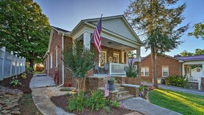 A brick house with a porch, American flags, and a well-maintained garden. - Modern, Sun-Lit Retreat w/ Fire Pit & Yard! (Jefferson City)