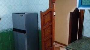 A kitchen with a refrigerator, a wooden door, and a tiled backsplash. - A 3-BR apt w FP, GV & 20 min to the sea & Muntazah (Al Mandarah Qebli, Montaza 2)