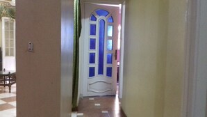 A hallway with a white door featuring blue glass panels and a decorative arch. - A 3-BR apt w FP, GV & 20 min to the sea & Muntazah (Al Mandarah Qebli, Montaza 2)