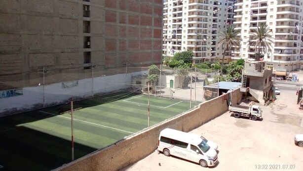 A residential area with a tennis court, a white van, and multi-story buildings in the background. - A 3-BR apt w FP, GV & 20 min to the sea & Muntazah (Al Mandarah Qebli, Montaza 2)