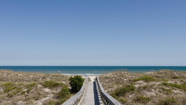 A wooden boardwalk leading to a beach with clear skies. - Stunning oceanfront end unit in Duneridge! (Wrightsville Beach)