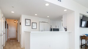A modern kitchen with white cabinetry, a central island, and recessed ceiling lights. - Stunning oceanfront end unit in Duneridge! (Wrightsville Beach)