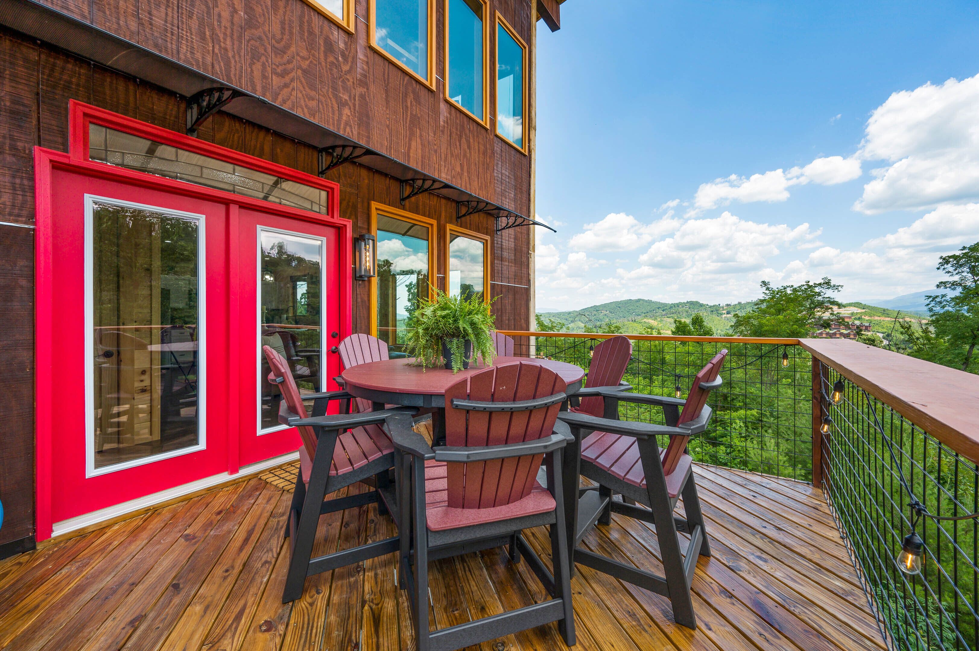 Una terraza de madera con una puerta roja y una mesa con sillas.