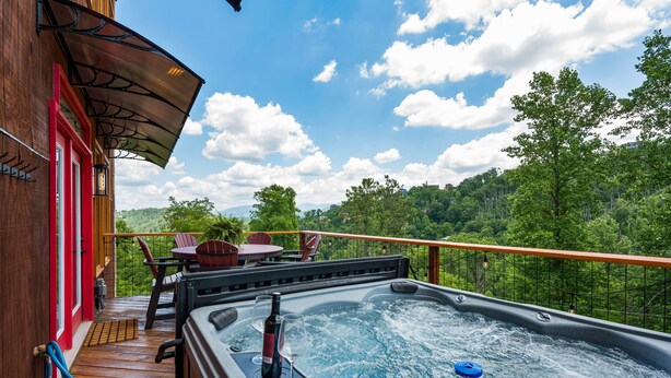 A hot tub on a wooden deck with a view of a forested hillside. - 4King Suites | Hot Tub | Game Room | Sunrise Views (Gatlinburg)