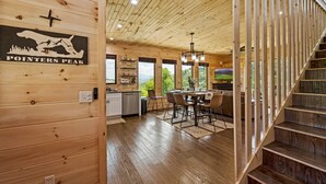 A wooden interior with a kitchen, dining area, and staircase. - 4King Suites | Hot Tub | Game Room | Sunrise Views (Gatlinburg)