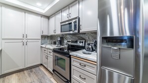 Una cocina moderna con electrodomésticos de acero inoxidable, armarios blancos y encimera de mármol.