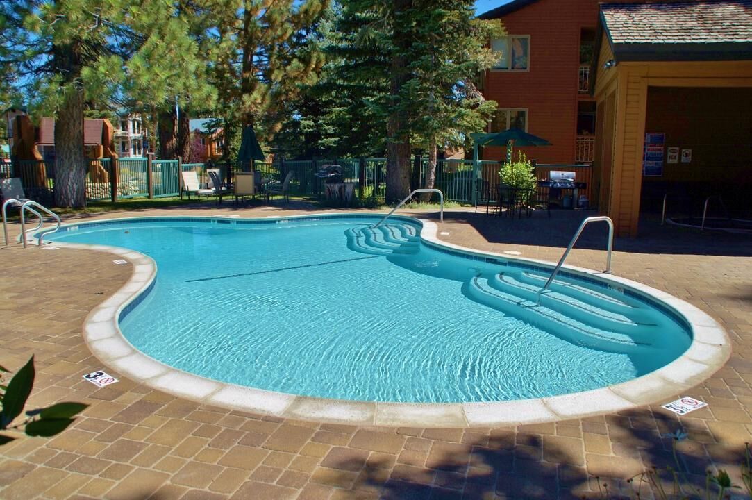 A swimming pool with a curved edge, surrounded by a brick patio.