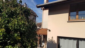 Una casa con techo de tejas, puerta de garaje y jardín con follaje verde.
