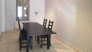 Un comedor con una mesa rectangular y seis sillas, una ventana con persianas y una pared con textura.