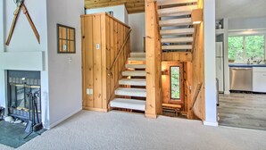 A modern interior with a wooden staircase leading to a kitchen area. - Cozy Lincoln Condo ~ 1 Mi to Loon Mountain! (Lincoln)