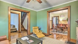 A spacious living room with a leather sofa, a coffee table, and a reclining chair. A staircase leads to another room, and a dining area is visible in the background. - Milwaukee Home < Half Mi to Lake Michigan! (Milwaukee)