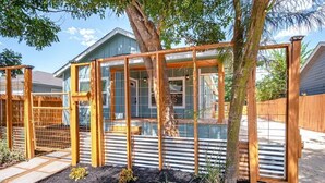 Une structure en bois dotée d’une paroi vitrée, entourée d’un jardin agrémenté de paillis et de plantes.