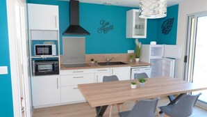 A modern kitchen with white cabinets, a wooden dining table, and a black microwave.